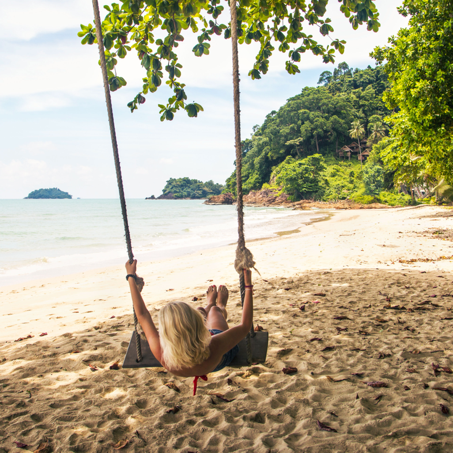Un niño columpiándose en una playa de Tailandia