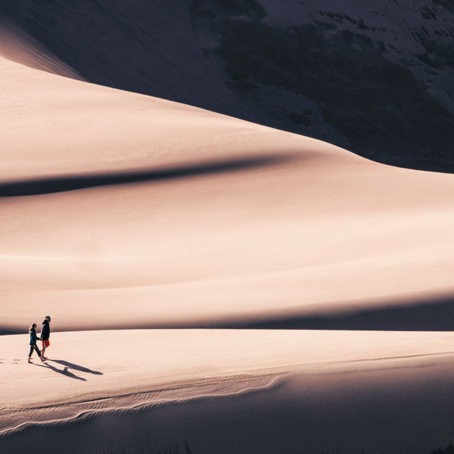 Two people walking on sand dunes