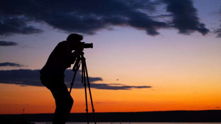 Silhouette de photographe en train de prendre un cliché sur fond de coucher de soleil