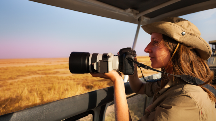 Femme à bord d'un 4x4 photographiant la savane