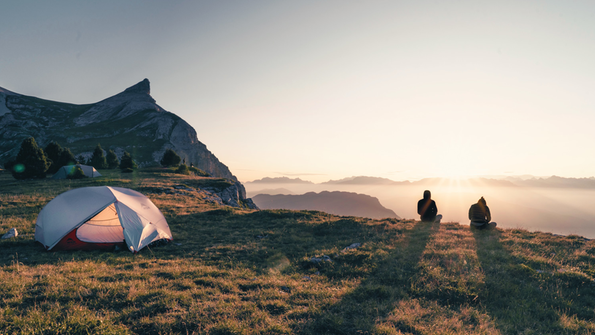 Wanderer mit Zelt bei Sonnenuntergang in den Bergen