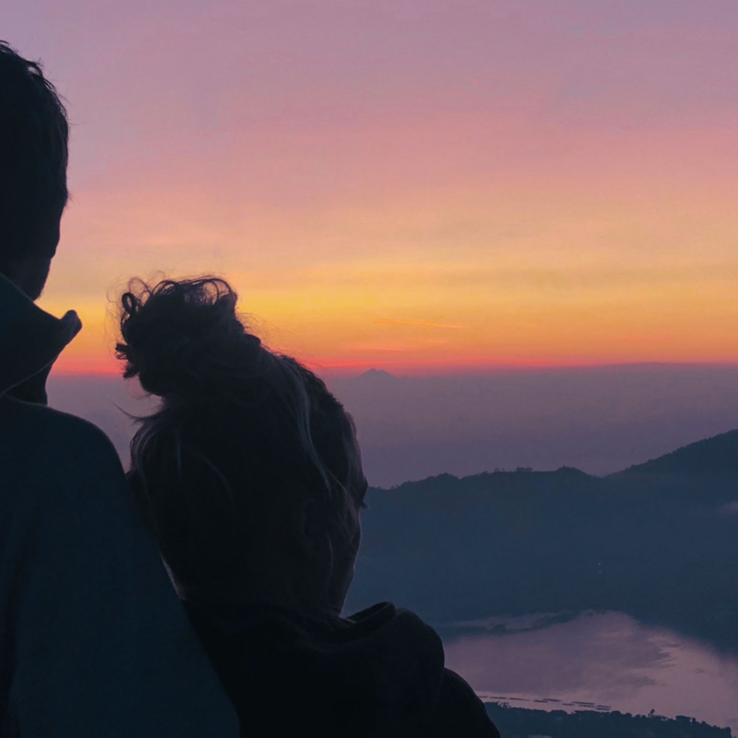 Couple admirant le lever du soleil face au mont Batur en Indonésie