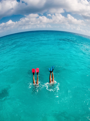 Couple de plongeurs dont les jambes dépassent de l'eau turquoise