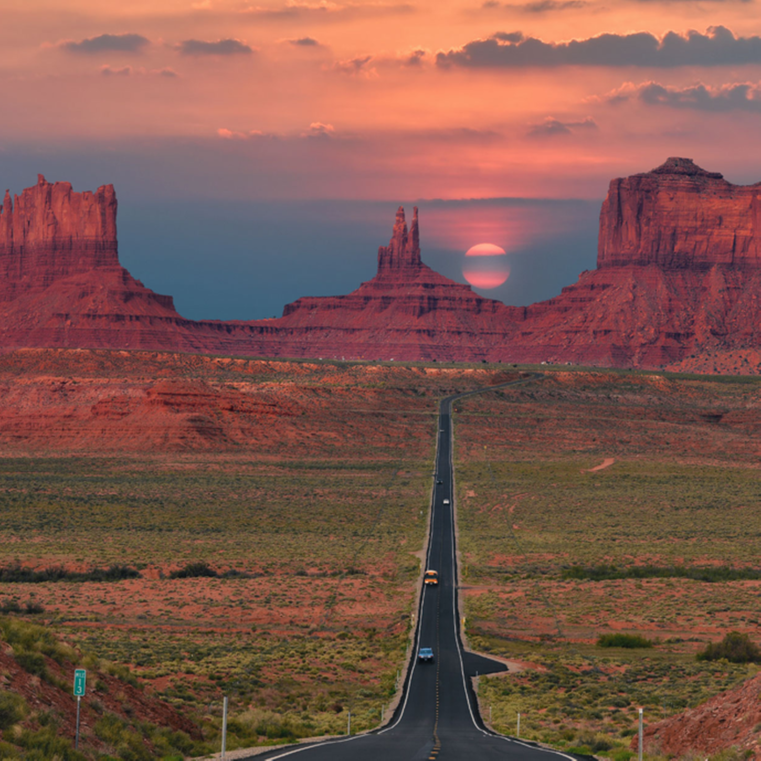 Route filant à travers Monument Valley sur fond de coucher de soleil.