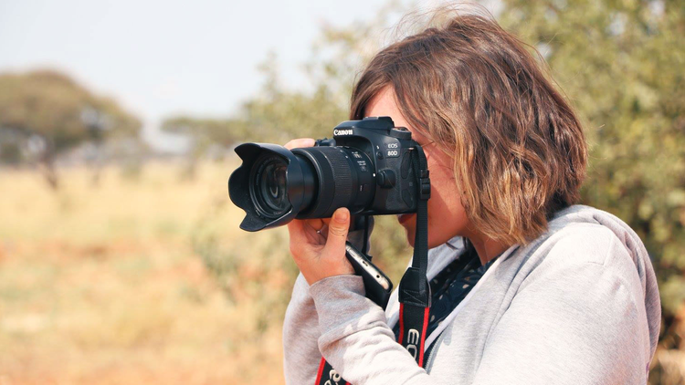 Une femme en train de faire des photos dans la savane