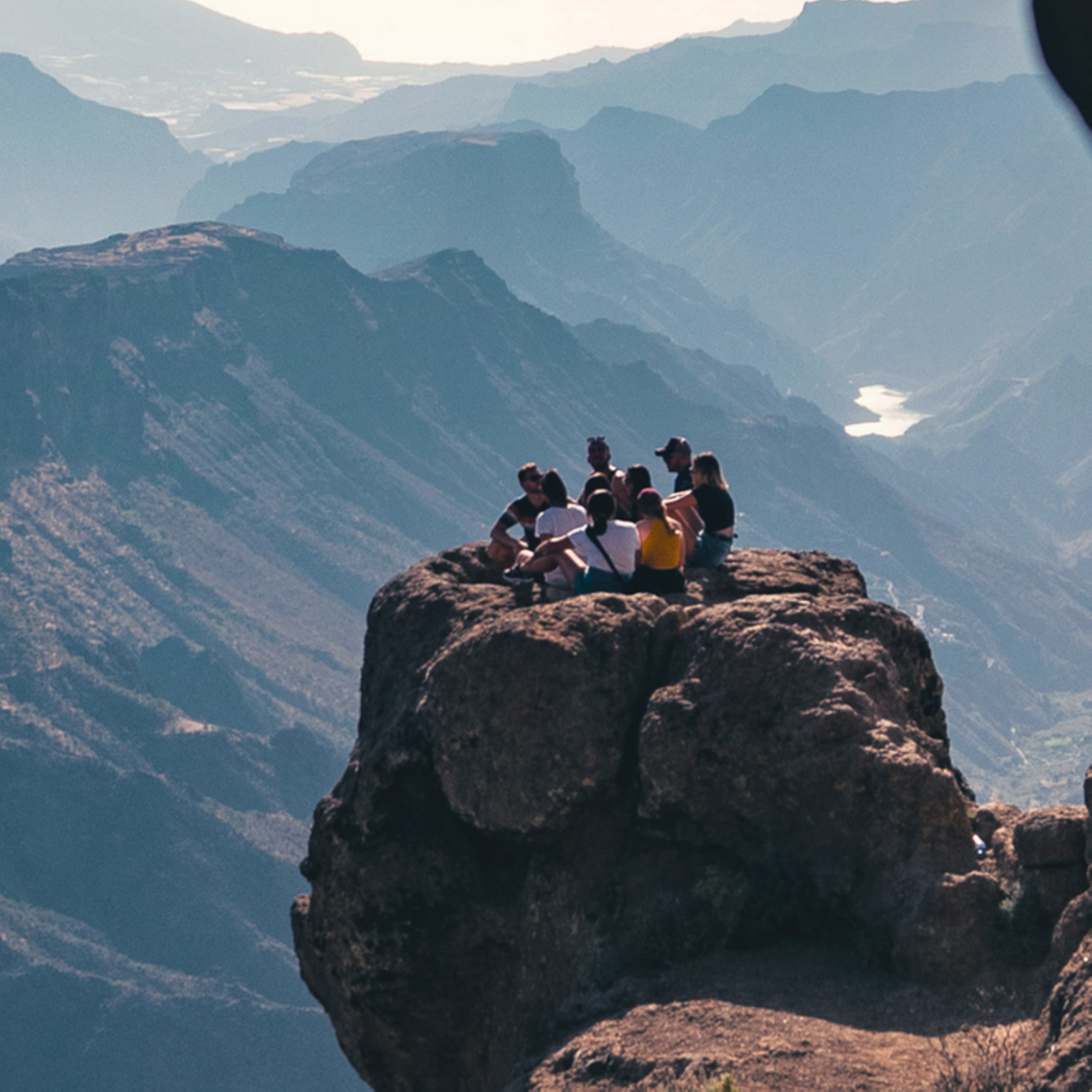 Reisende sitzen in luftiger Höhe auf einem Felsen