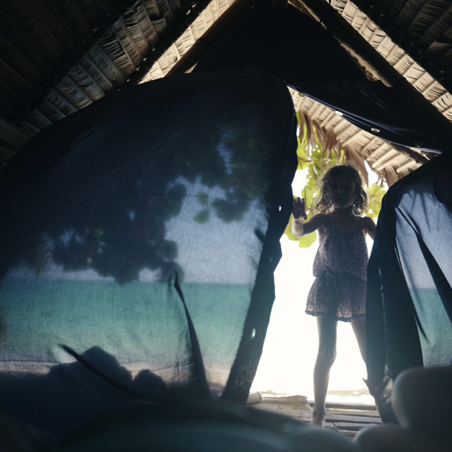 Une petite fille entre dans une tente sur la plage