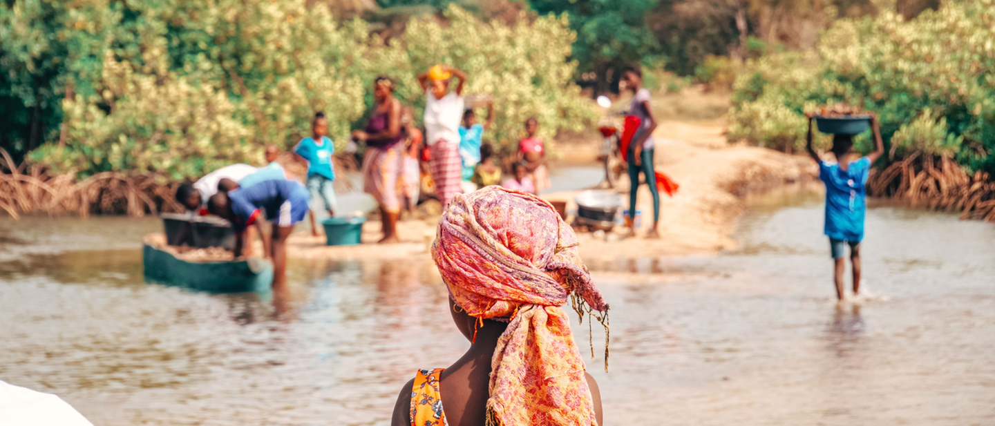 Un enfant de dos observant un groupe de personnes au bord d'une rivière
