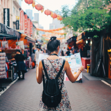 Jeune femme dépliant une carte dans une rue d'une ville asiatique