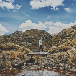 randonneuse traversant un pont de bois au milieu des montagnes en Equateur