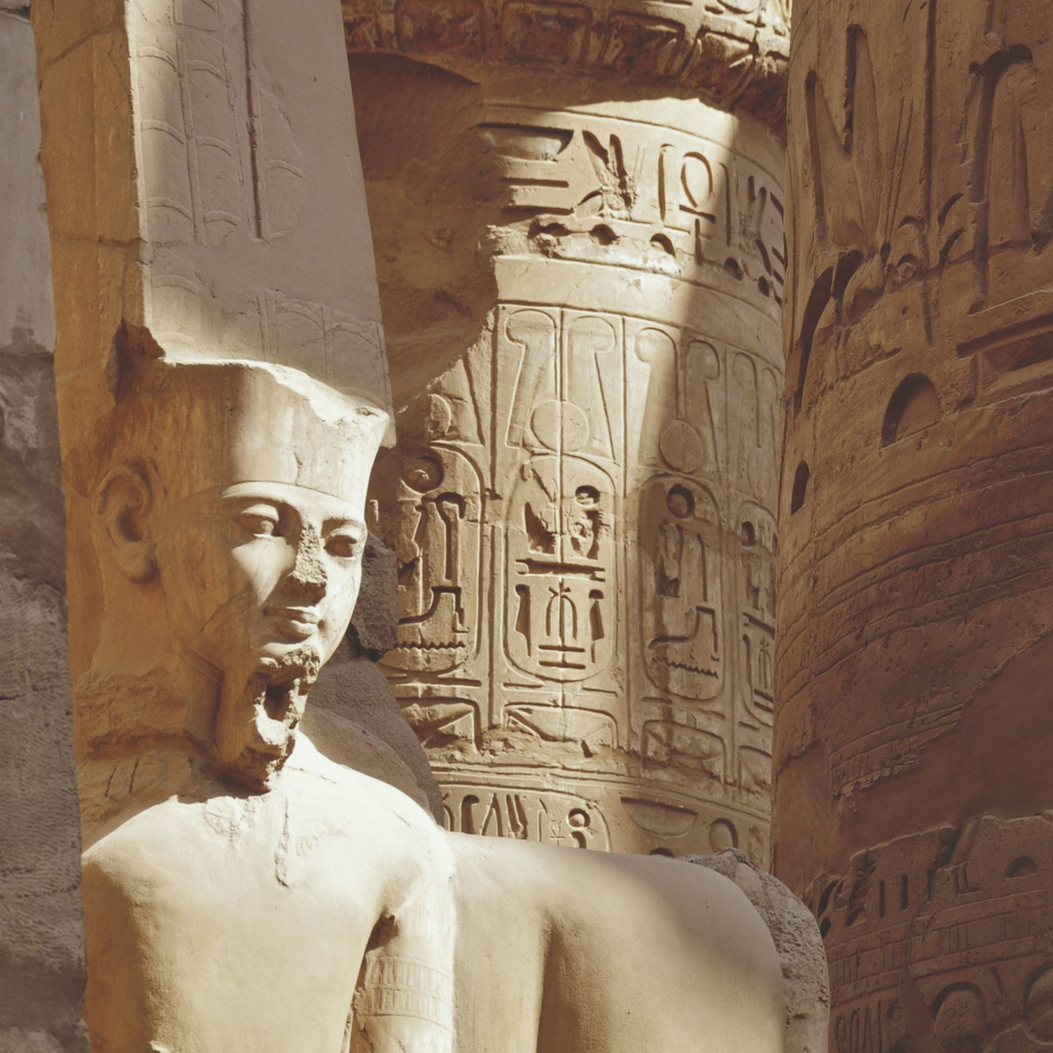 Statue de pharaon et colonnes couvertes de hiéroglyphes au temple de Karnak
