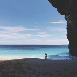 Silhouette de femme sur une plage entourée de falaises à Nusa Penida