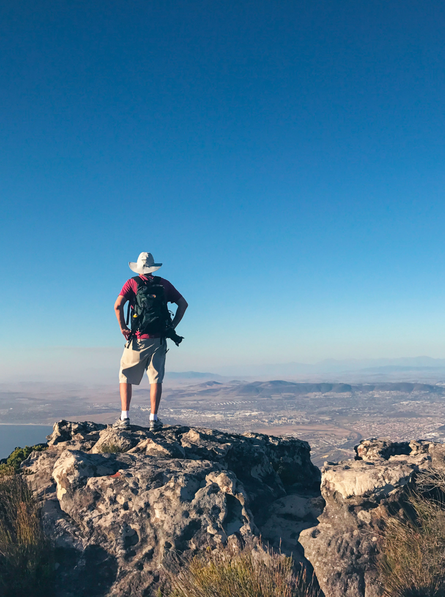 01 Man enjoying the view from top of Table Mountain in Cape Town, South Africa. The city and ocean can be seen below. Taken in April 2017 - Fall/Autumn.