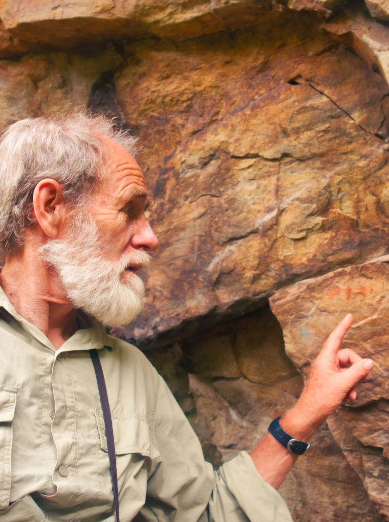 03 Old man points at the ancient bushman paintings. Shot in Hottentots Holland Mountains, Vergelegen area, near Somerset West, Western Cape, South Africa