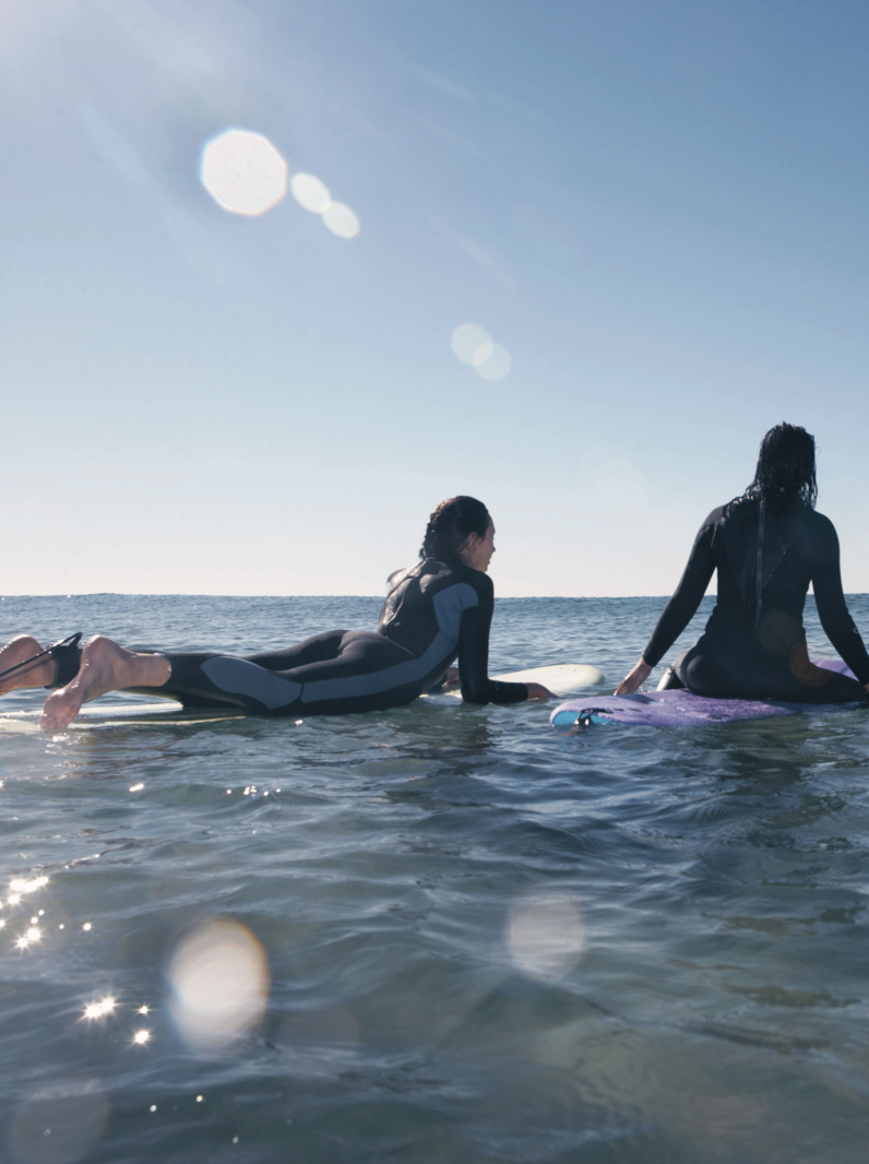 03 Three teenage girls (16-18) on surfboards in sea, rear view