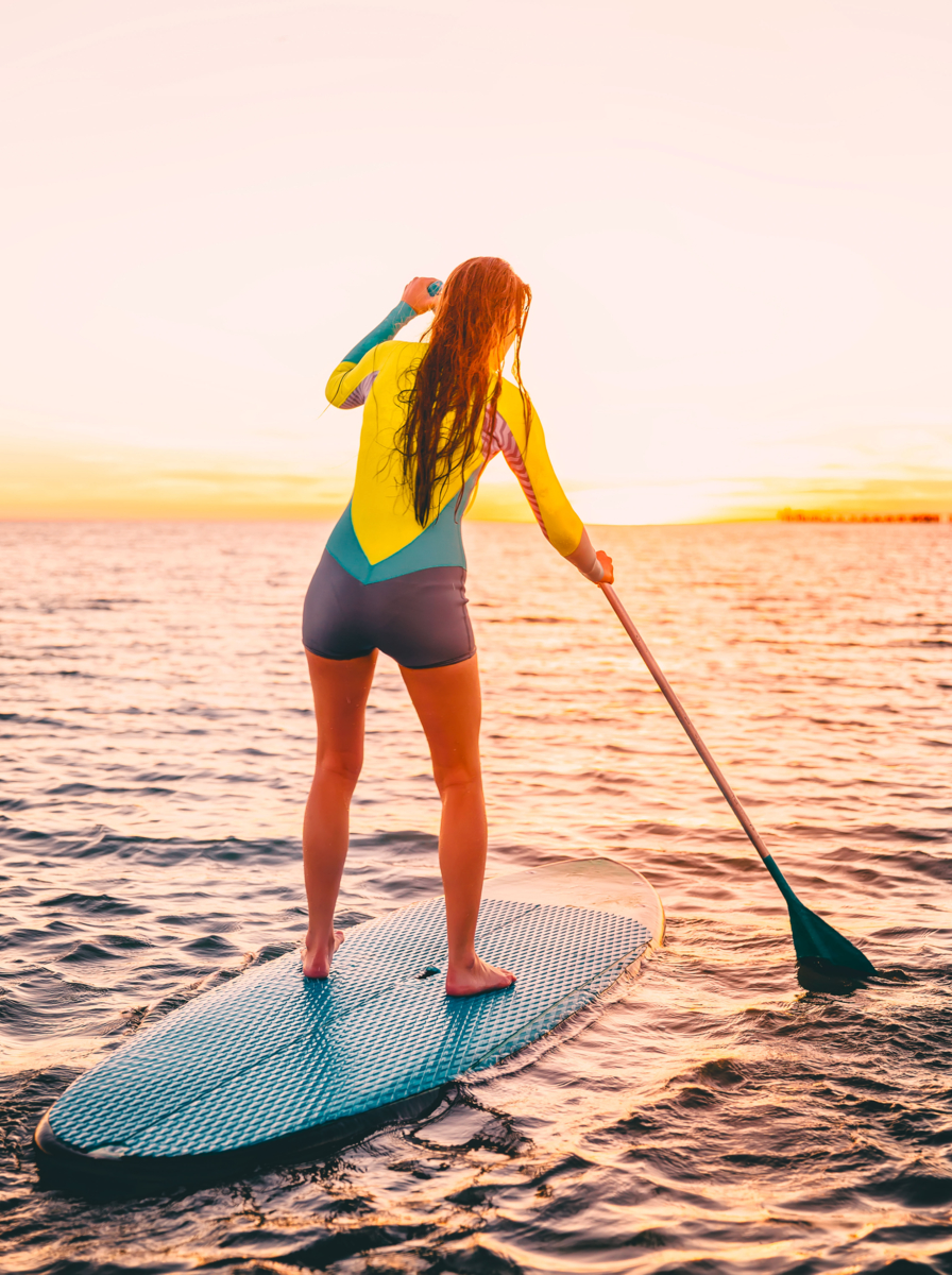 03 Attractive young woman stand up paddle surfing with beautiful sunset or sunrise colors