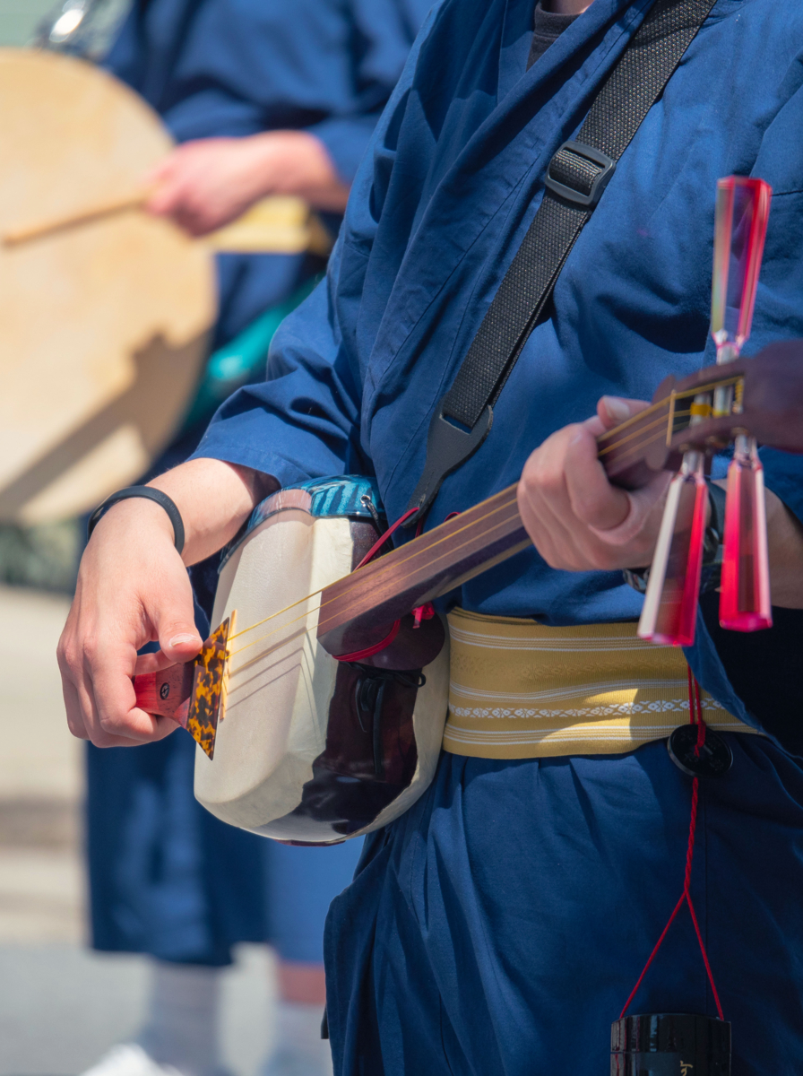Man playing a traditional Japanese instrument shamisen as part of a parade