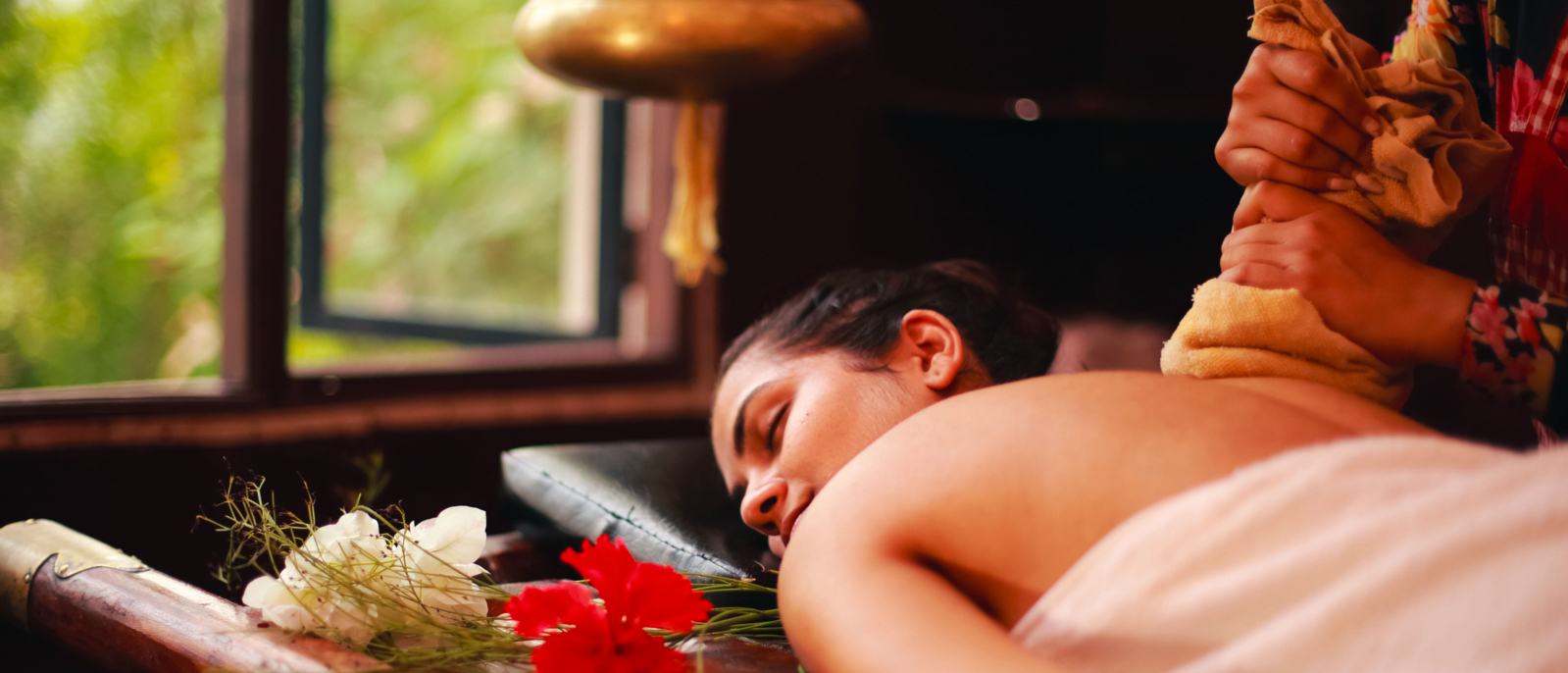 Female therapist treating a young lady in an ayurvedic spa following Indian traditional method