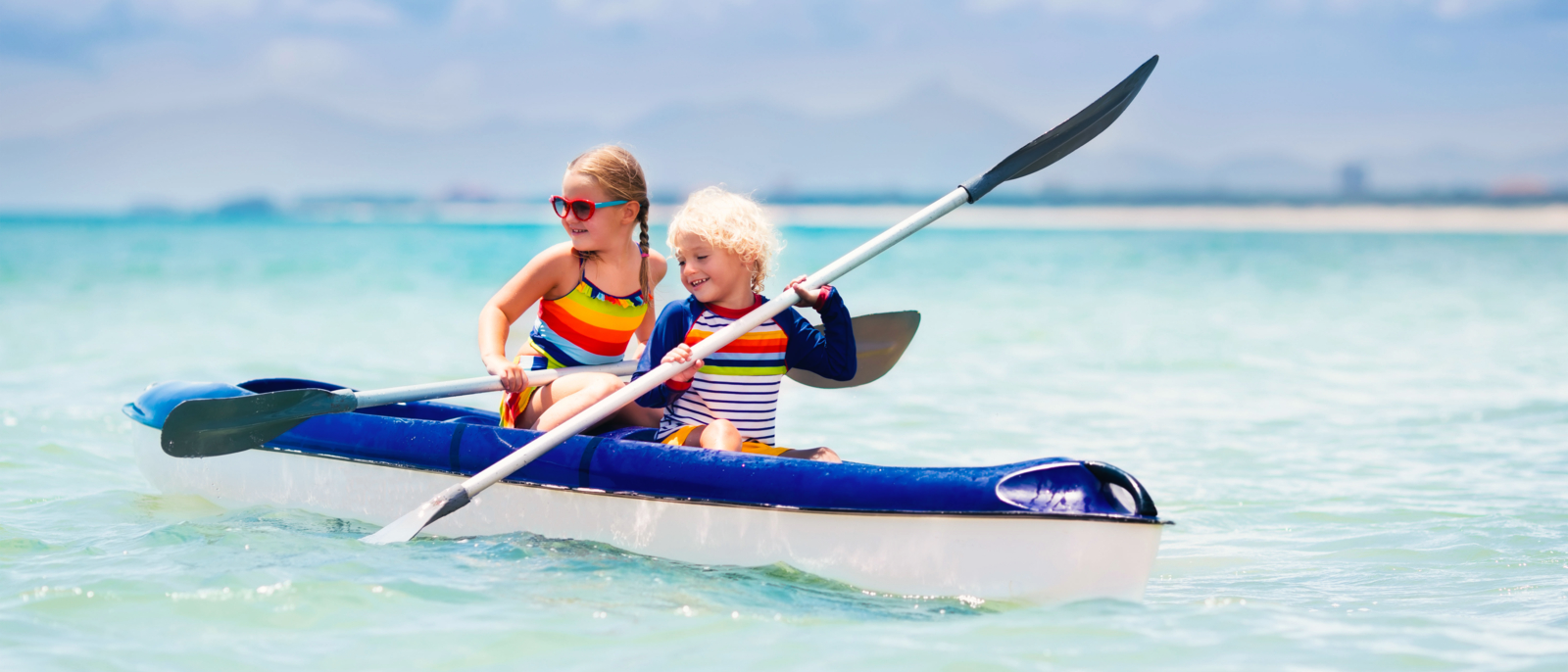 Kids kayaking in ocean. Children in kayak in tropical sea. Active vacation with young kid. Boy and girl in canoe on beautiful beach. Holiday activity with preschool child. Family summer fun.