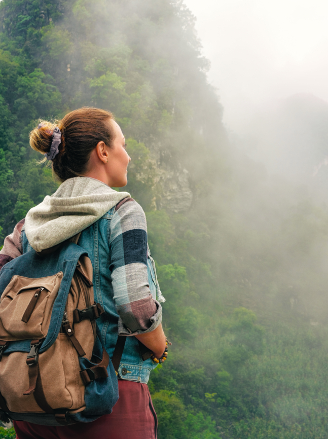 Traveler with backpack in mountains enjoying on view of foggy karst mountains North Vietnam.