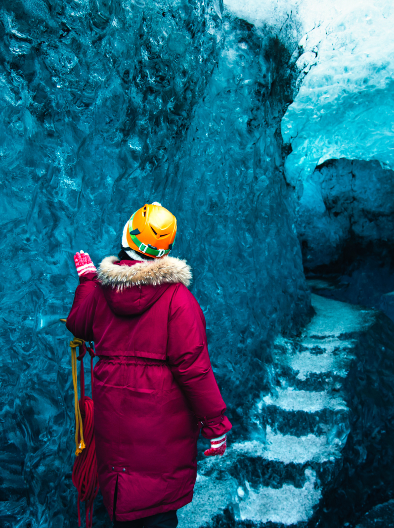 Woman exploring blue ice cave in Iceland back view