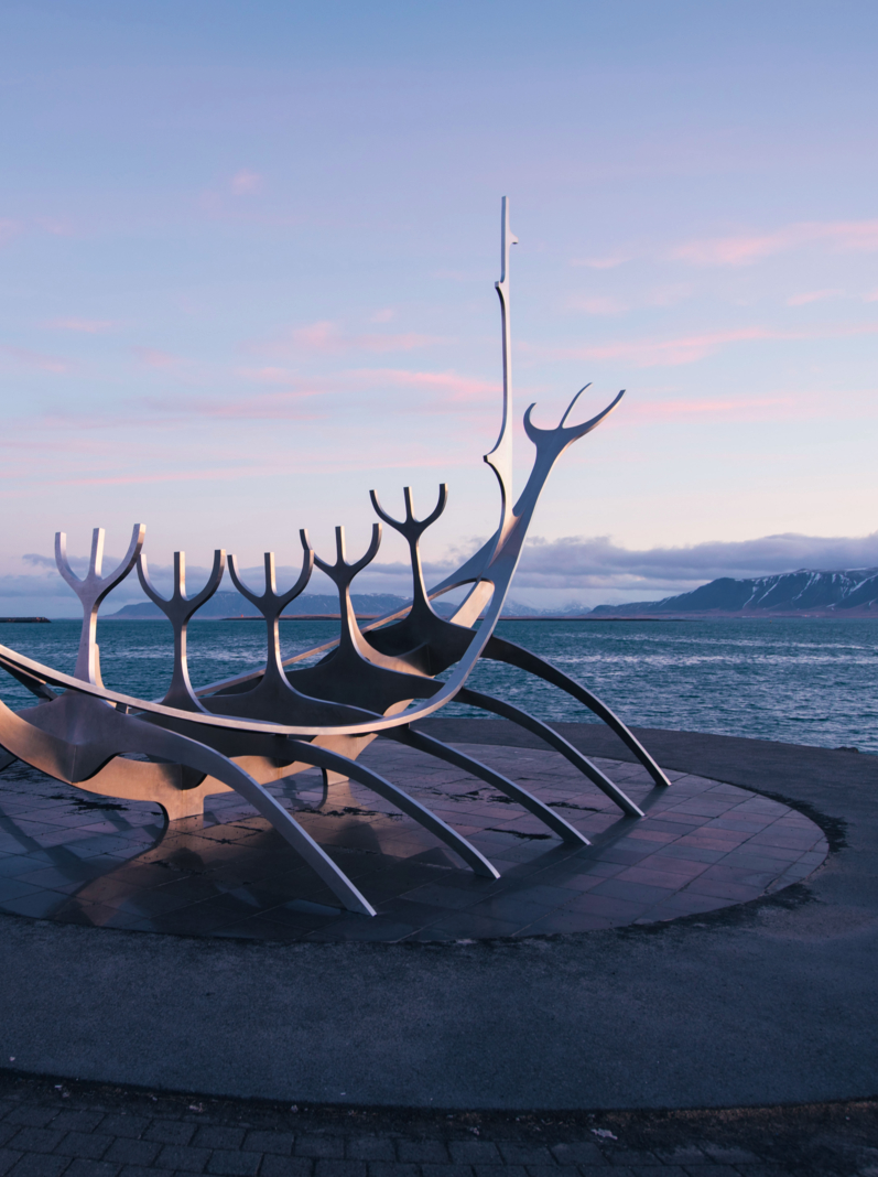 the monument at reykjavik bay have the fog on the mountain at background
