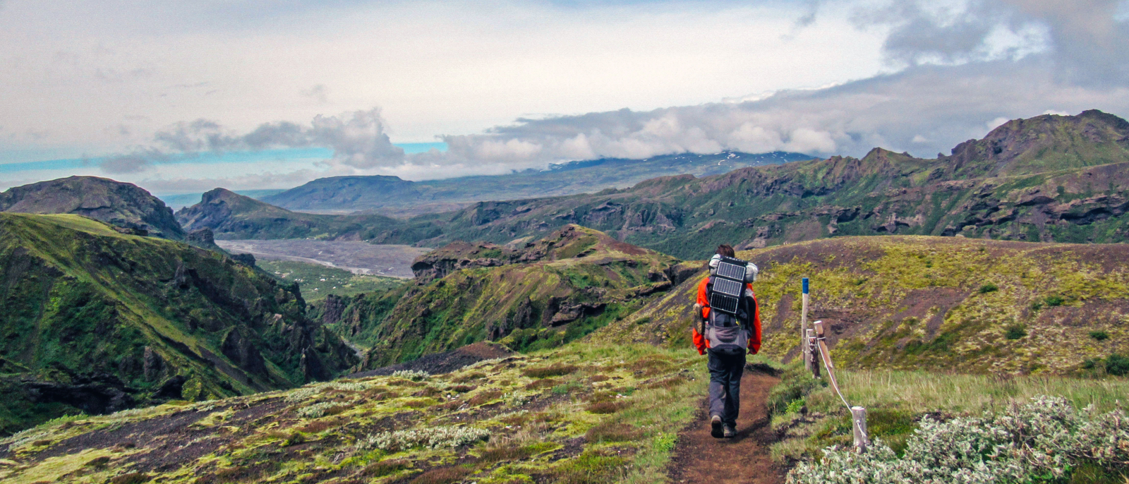 Hiker man alone into the wild admiring volcanic landscape of green Icelandic valley. Laugavegur hiking trail, summer vacations outdoor in highlands, Thorsmork