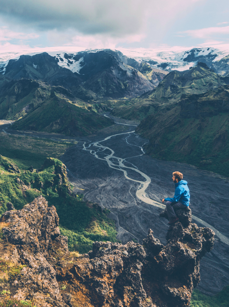 Scenic view of man in blue raincoat looking at Thórsmörk river valley in Iceland Highlands