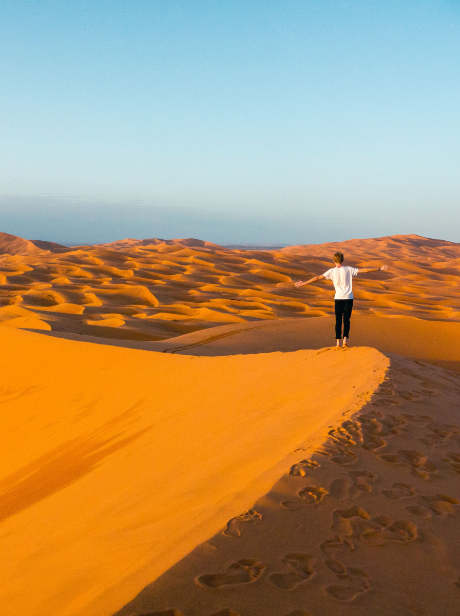 Man walking through the golden sand dunes of Erg Chebbi near Merzouga, Morocco: Balancing act in the endless sea of sand