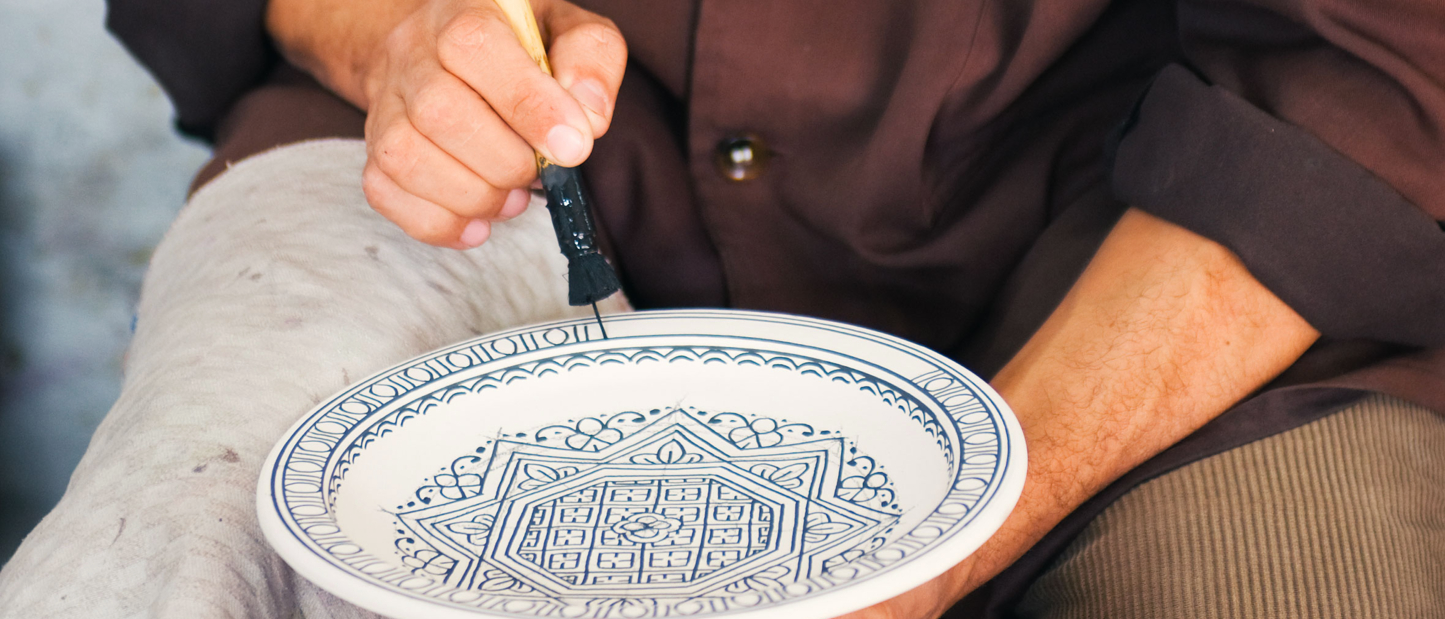 An artist painting a traditional patterned plate in Morocco
