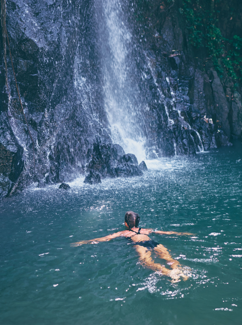 Travel and nature. Young woman swimming in tropical waterfall pool