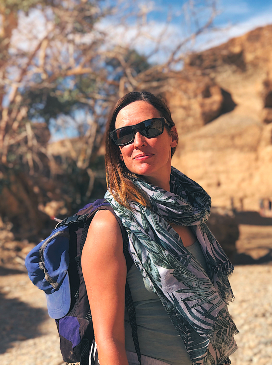 Beautiful mid age woman with sunglasses and backpack in a arid canyon Sesriem Canyon Namib