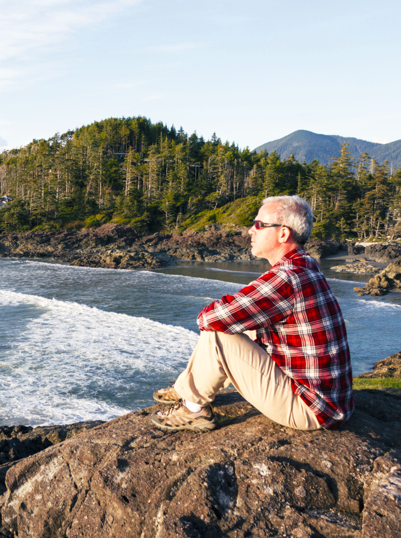 One adult man looking at the waves in Pacific Rim National Park Reserve a Canadian national park reserve in near Tofino on Vancouver Island, British Columbia. comprising three separate regions: Long Beach, the Broken Group Islands, and the West Coast Trail