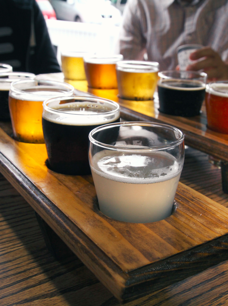 Twelve beer samples being shared at a table by some men.