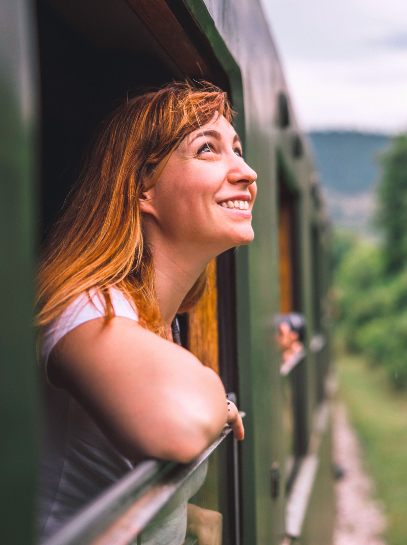 Female tourist traveling in train standing out of window train and looking beautiful nature