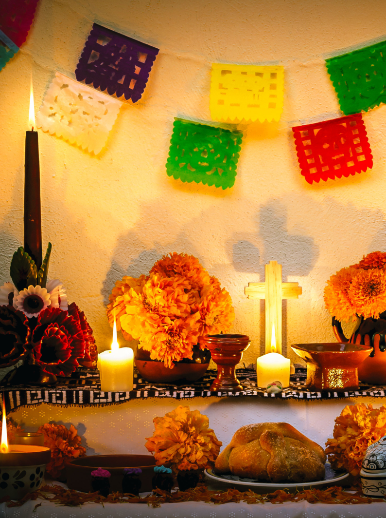 Traditional mexican Day of the dead altar with cempasuchil flowers, bread "pan de muerto", "papel picado" ornaments and candles.