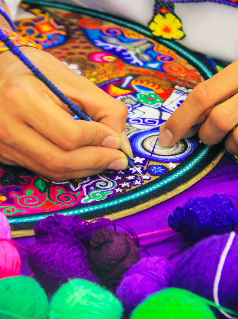 Close up of a Mexican man working of his handcraft with bokeh of yarn in front