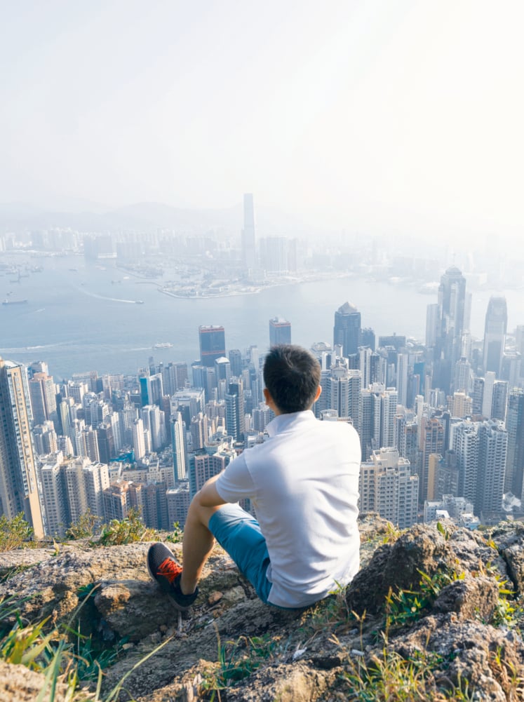 Men sitting on the top of mountain and looking cityscape Hong Kong