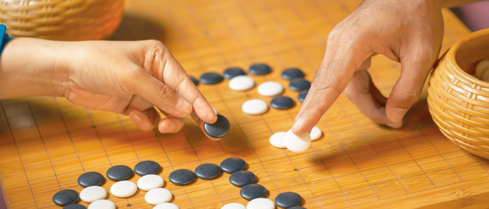 Go board game playing. A competitor is placing a marble piece on a Go board game