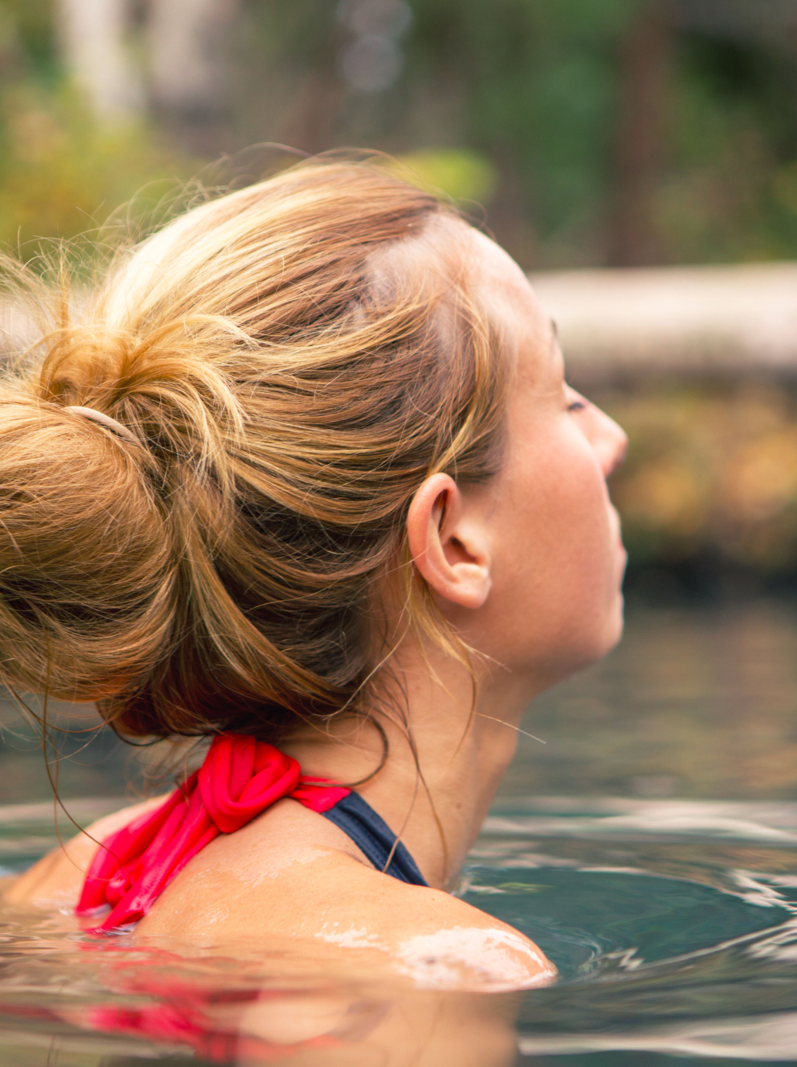 Young woman enjoying a natural bath at the hot springs. Autumn season