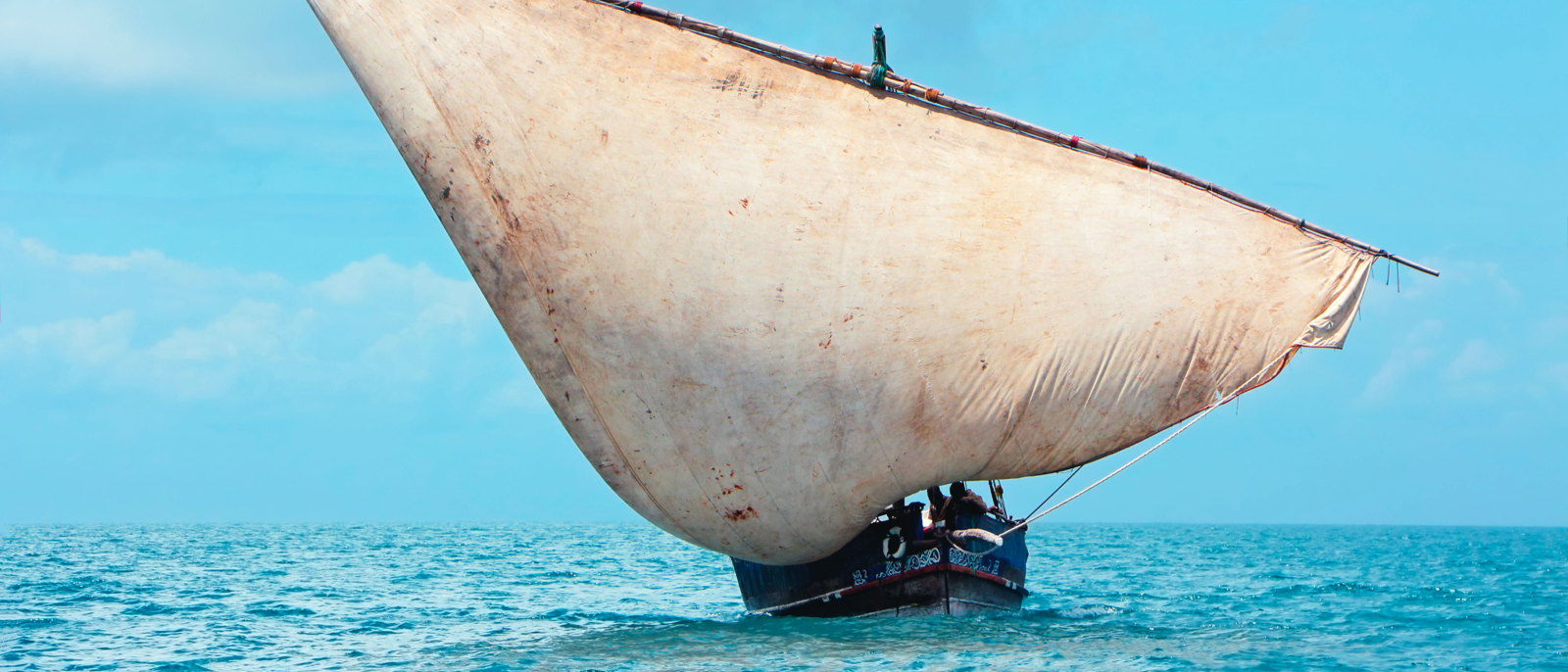 Wooden sailboat (dhow) on the open sea with clouds, Zanzibar