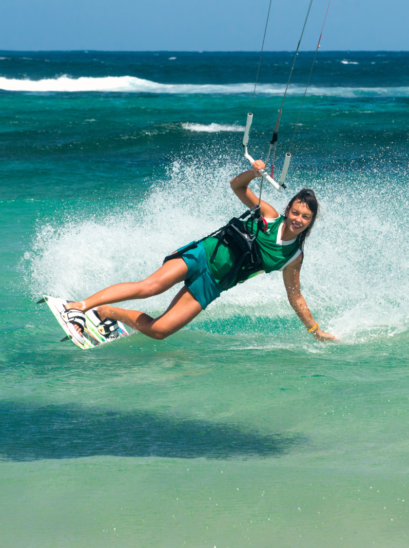 young beautifil girl - kiter riding in the clear waves of the Indian Ocean on the island of Mauritius. Kiting on a background of waves in the spray of ocean