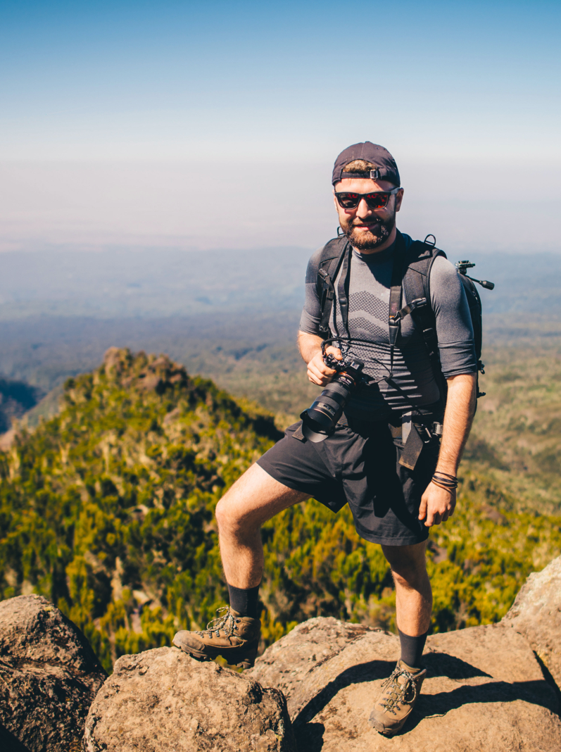 man standing on rocks, holding camera, Kilimanjaro mountain