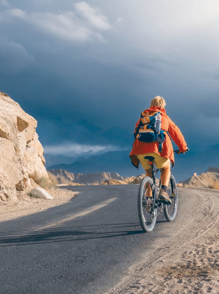 Bike tourist rides on Himalaya mountain road on way to buddist monastery