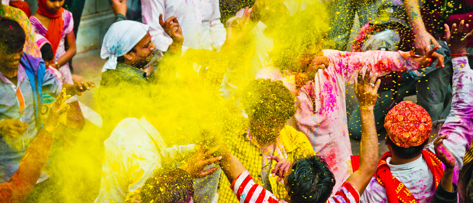 crowd of paint covered villagers celebrate Holi by dancing and throwing colors to each other. Holi is the most celebrated and colorful religious festival in India.