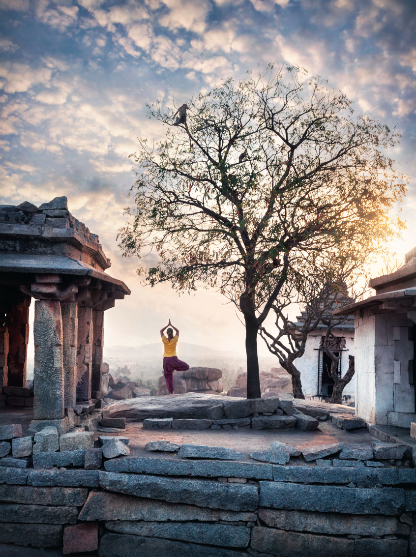 Woman doing yoga near ancient ruins on Hemakuta hill in Hampi, Karnataka, India