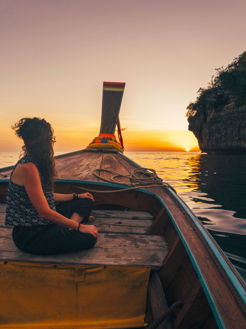 Young woman on a longtail boat in Thailand during sunset, Phi Phi Island