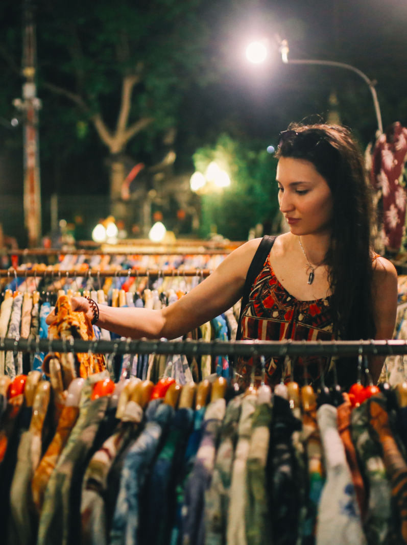 Vintage toned image of a young tourist woman, browsing the evening street market near Chatuchak in Bangkok, Thailand. Bargain priced clothing, food, and all kinds of stuff for everyday use.
