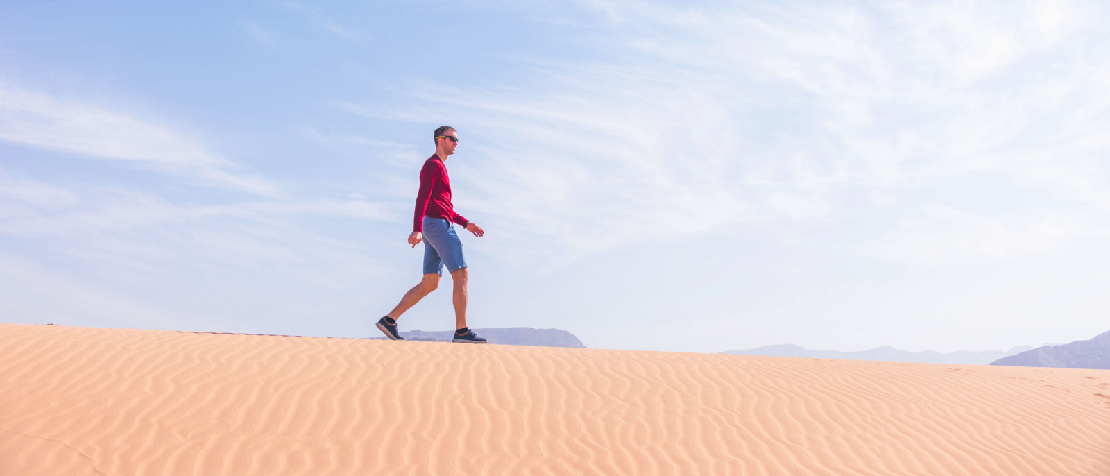 Tourist walks on the sand dune. Wadi Araba desert, Jordan landscape