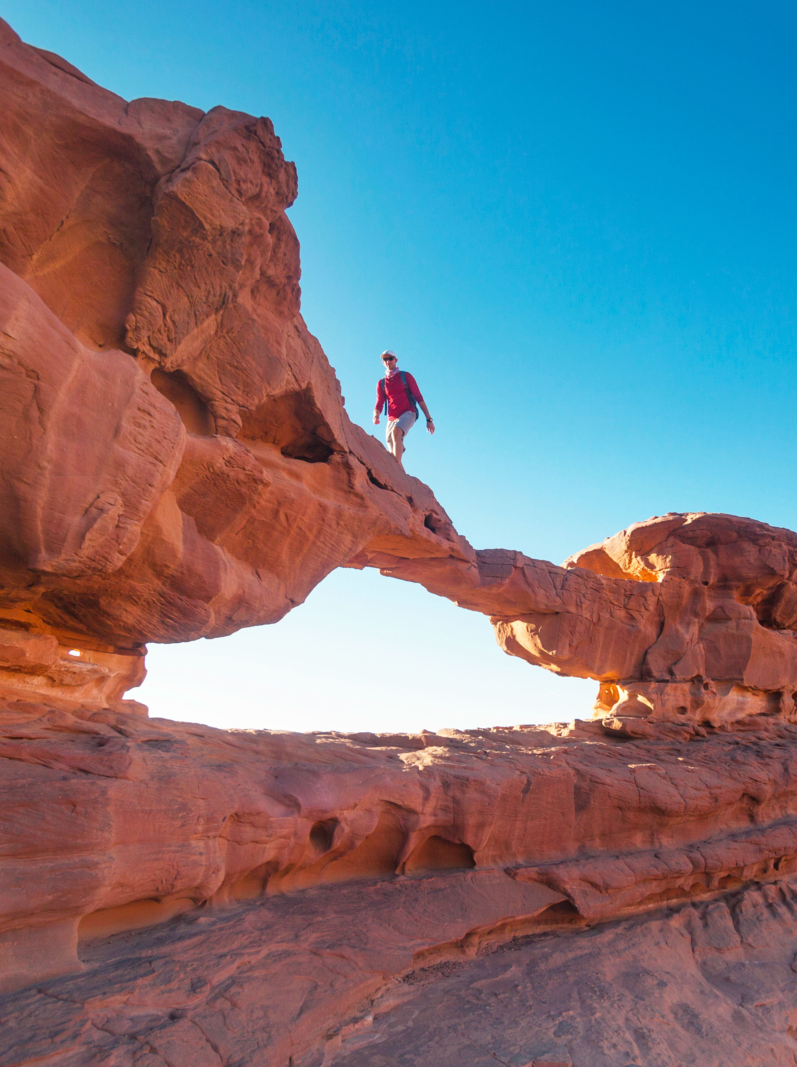 Touriste sur un rocher dans le désert de Wadi Ram. Arc de pont de pierre. Site de Jordanie
